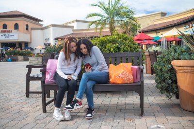 Twin teens looking at phone while shopping